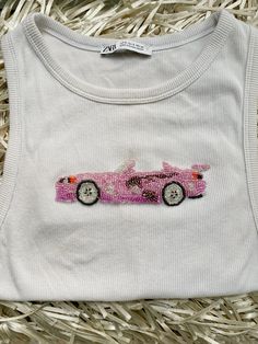 a white t - shirt with a pink car embroidered on it