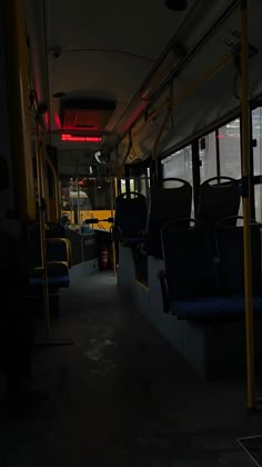 the interior of a public transit bus with its lights on and empty seats at night