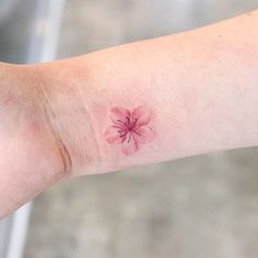 a small pink flower on the left wrist and right hand with it's petals sprout out