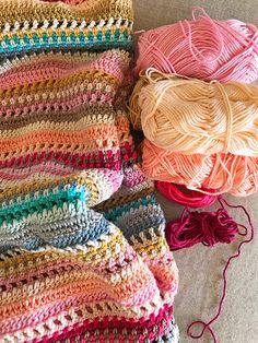 several balls of yarn sitting on top of a bed next to some crochet