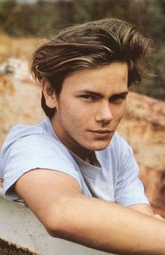 a young man leaning on a wall with his arms crossed