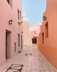 an alley way between two pink buildings with small windows on each side and one window in the middle