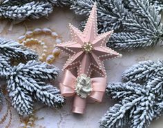 a pink star ornament sitting on top of a table next to pine cones