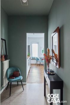 the hallway is painted green and has a blue chair in front of it, along with two mirrors on the wall