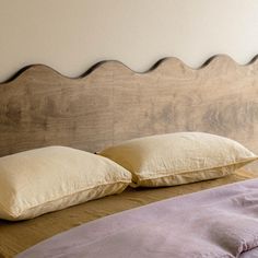 a bed with two pillows on top of it and a headboard made out of wood