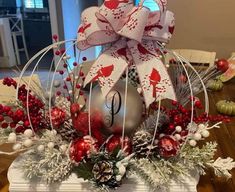 a christmas centerpiece with an ornament and bow on it, sitting on a table