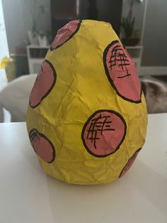 a yellow paper mache with chinese characters on it sitting on a white table in front of a cat