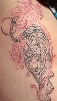 a tiger tattoo on the back of a woman's stomach with flowers around it