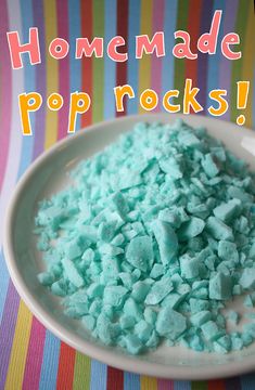 a white bowl filled with blue and green colored rocks on top of a striped table cloth