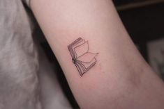 a small book tattoo on the arm