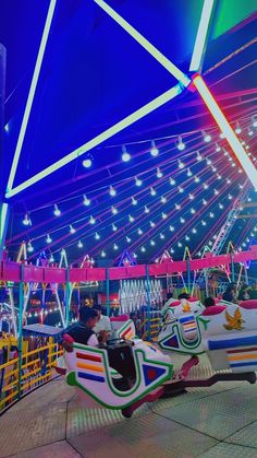 an amusement park at night with people on the rides and colorful lights in the background