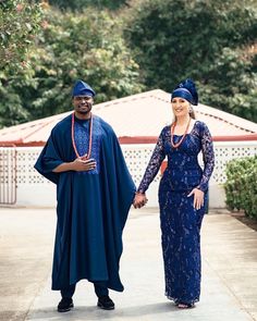 a man and woman dressed in blue holding hands