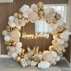 a happy birthday balloon arch with white and gold balloons, pineapples and succulents