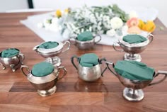 a group of silver cups sitting on top of a wooden table covered in green napkins