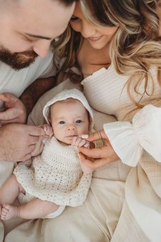 a man and woman holding a baby in their arms