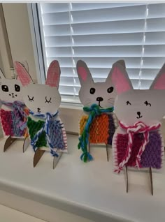 three paper rabbits sitting on top of a window sill next to a pair of scissors