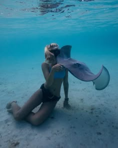 a woman is sitting on the sand with a large object in her hand under water