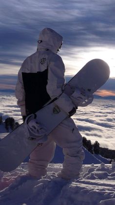 a snowboarder is standing in the snow holding his board and looking at the sky