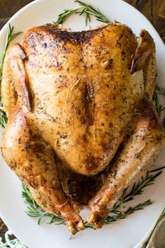 a roasted turkey on a white plate with rosemary garnish and the words triggerer smoked turkey