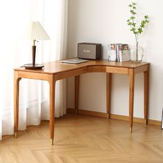 a wooden desk with a lamp and books on it in front of a white wall