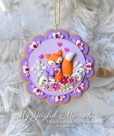 an ornament hanging from a tree decorated with flowers and a fox on it