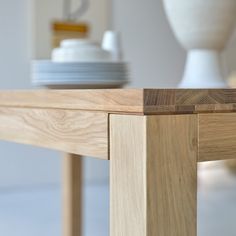 a close up of a wooden table with plates on it and a vase in the background