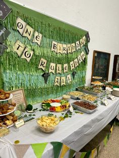 a table filled with lots of food next to a green wall