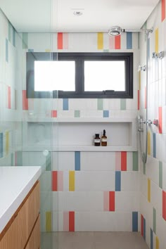 a bathroom with colorful tiles on the walls and floor, along with an open window