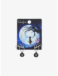 a pair of earrings with black and white charms on them, featuring a girl walking in front of a full moon