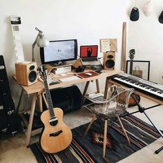 a desk with a guitar, keyboard and monitor on it