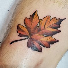 an orange and black leaf tattoo on the leg