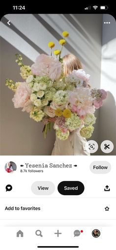 a woman holding a bouquet of flowers in her hands and looking at the screen on her phone