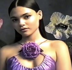 a woman in a purple dress standing next to a man with flowers on his chest