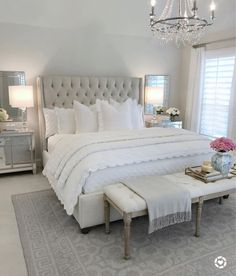 a bedroom with a bed, nightstands and two lamps on either side of the window