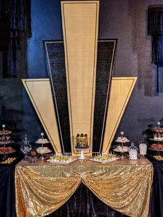 a table topped with cakes and desserts on top of a black cloth covered table