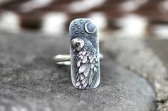 This listing is for one striking and unique sterling silver barn owl and moon ring. It features a detailed and dimensional barn owl under a crescent moon with stars. This thick and sturdy owl focal is fired onto 9 gauge half round wire. This ring is perfect for any owl and nature lover! It looks great solo or stacked with other rings and bands. - Choose your size at check-out! - Owl focal measures 28 mm by 12mm. - Ring band is 2mm wide by 1.5mm thick. - Made to order just for you! Please take note of estimated delivery times in the shipping section at checkout! Want to stack it with some awesome textured silver stacking bands? Find them here: https://www.etsy.com/listing/532906393/silver-stacking-rings-simple-silver-ring?ref=shop_home_active_16 Not sure of your ring size? Purchase one of t Barn Owl Ring, Witch Ring, Witch Rings, Ring Moon, Owl Ring, Handmade Silver Jewellery, Silver Rings Simple, Witch Jewelry, Owl Jewelry