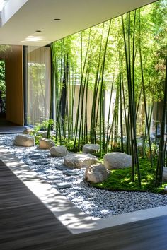 the interior of a modern house with bamboo trees and rocks on the floor, along with green grass