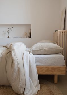 an unmade bed with white sheets and pillows