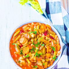 a bowl filled with pasta and vegetables on top of a checkered cloth next to a fork