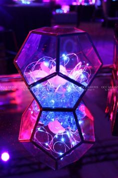 a glass vase filled with lights on top of a table