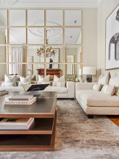 a living room filled with white furniture and lots of mirrors on the wall above it