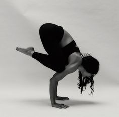 a woman is doing a handstand on one leg with her legs bent forward