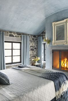 a bedroom with a fireplace and stone walls