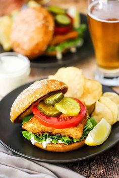 a black plate topped with a sandwich and potato wedges next to a glass of beer