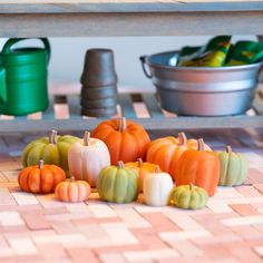 several small pumpkins are sitting on the floor next to two buckets and a table