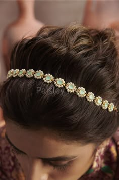 a close up of a woman wearing a headband with pearls and stones on it