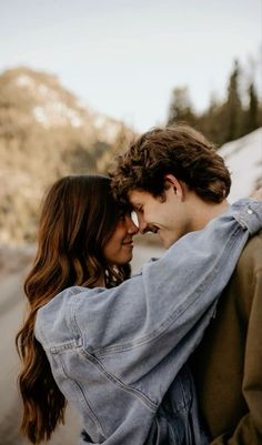 a man and woman standing next to each other with their arms around each other as they look into the distance