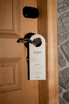 an open door with a paper on the handle and a sign hanging from it's side