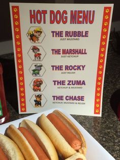 two hot dogs on buns with ketchup and mustard next to a sign