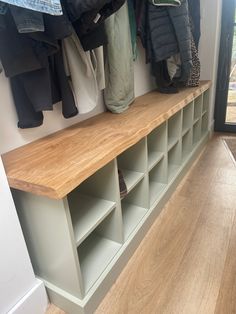 a coat rack with several coats hanging on it's sides, and some shoes in the background